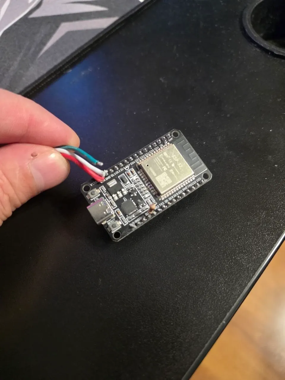 Плата ESP32 DevKit в руке, к ней припаяны провода